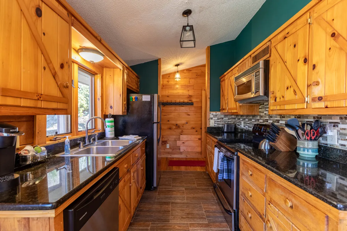A kitchen interior featuring granite countertops, ample wooden cabinets, and modern appliances. Natural light streams in through a window, illuminating the workspace and creating a homely atmosphere ideal for family gatherings and festive cooking.